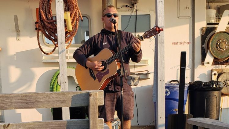 man playing guitar and singing on boat