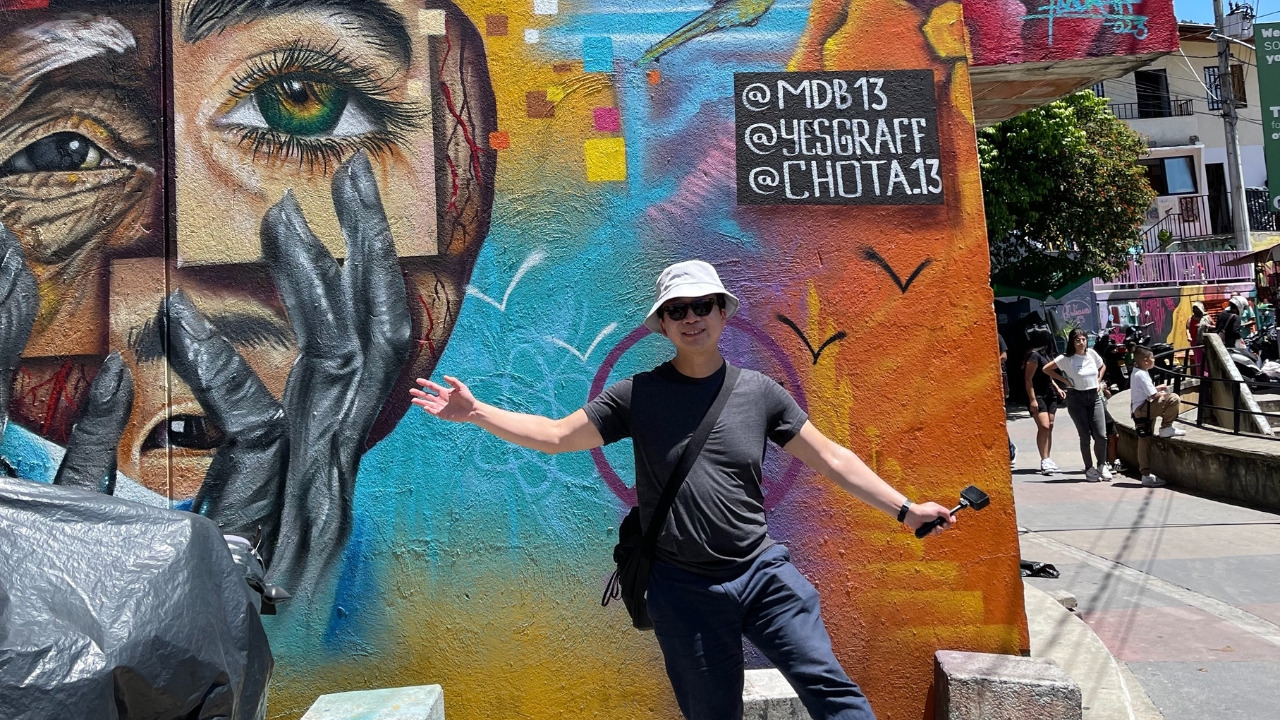 King posing in front of a mural, solo in Medellin, Colombia