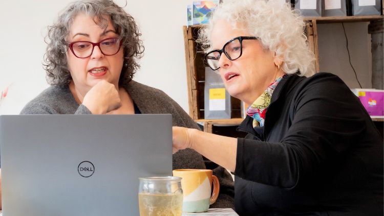 Tracey and Janice looking at laptop searching for trips for solo travelers