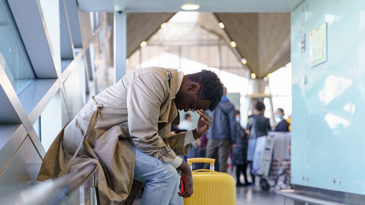 man in airport with head in hands experiencing solo travel anxiety