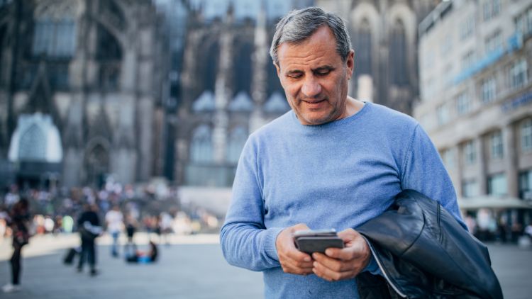 man in town square using his phone while traveling