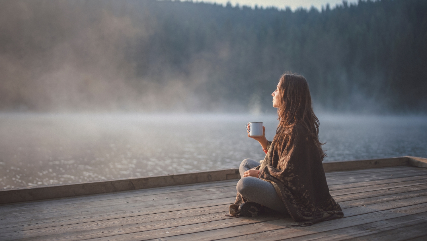 woman sitting on dock with cup of coffee