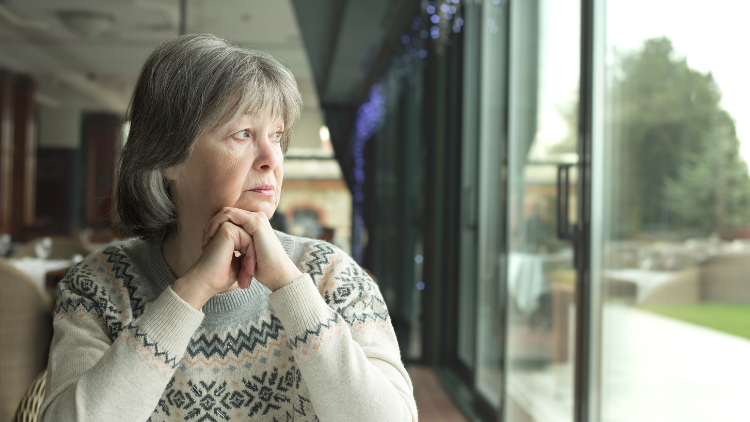 This image of a woman staring out a window exemplifies the solo travel myth that you will be lonely.