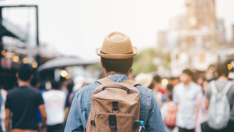 man with backpack walking on busy street